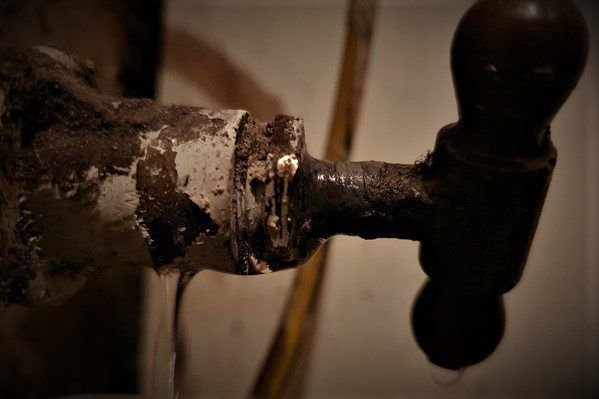 Fast Fix plumber using a wrench on pipework under a basin